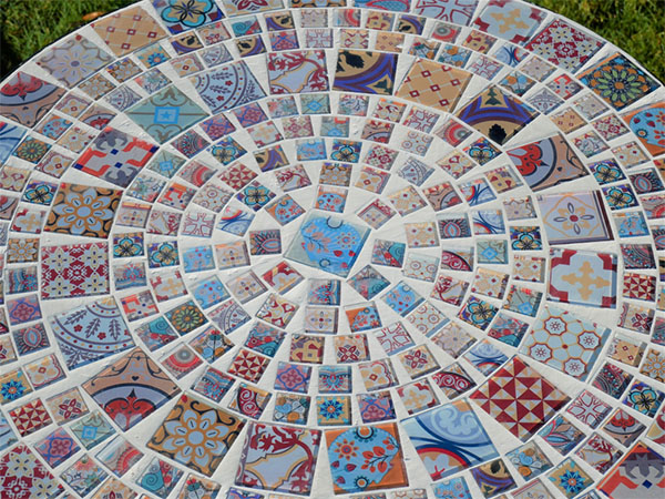 Close up image looking down onto the glass mosaic pattern on the top of the mosaic garden table for two